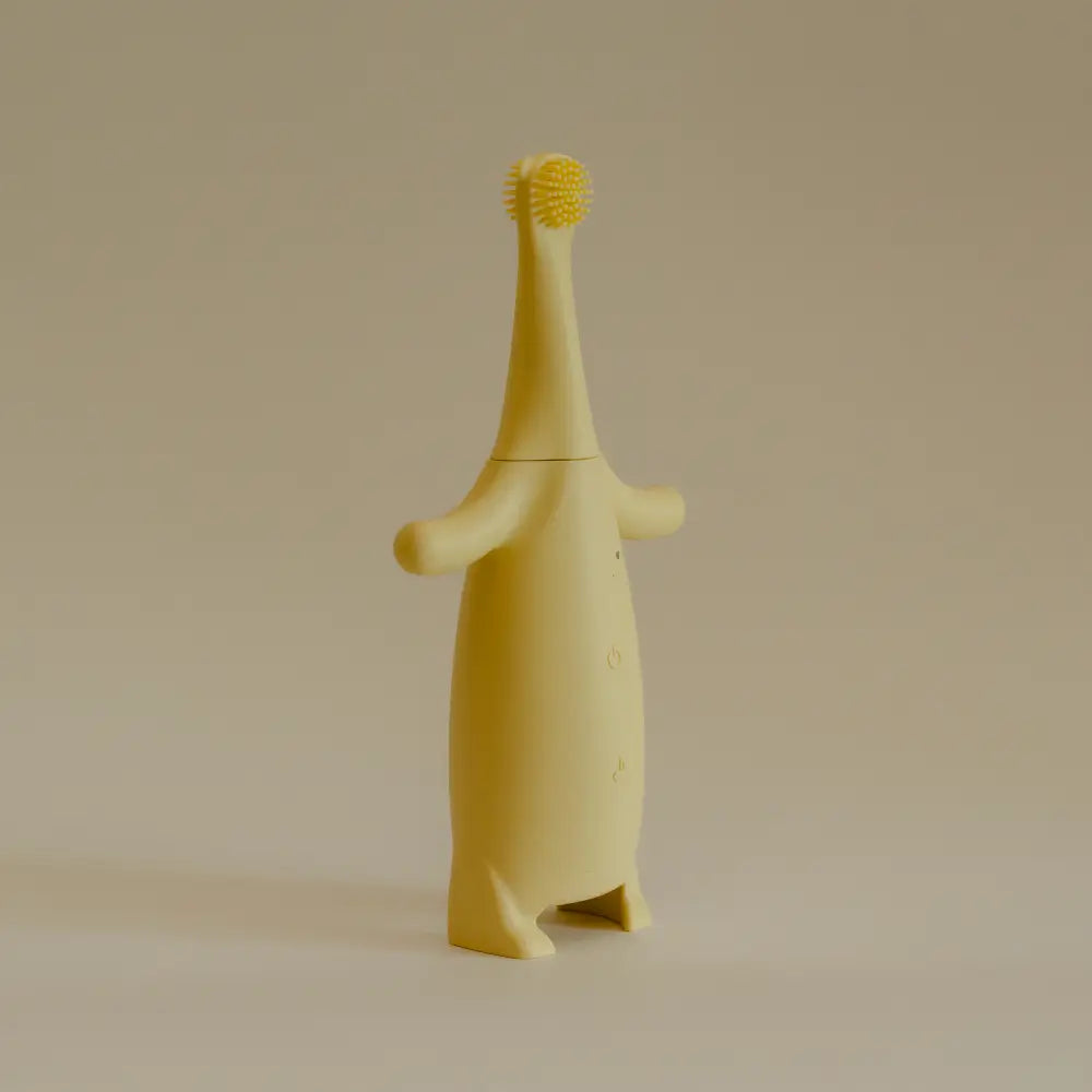 Little Brushies Yellow children's toothbrush with a stand on a beige background
